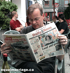 Kevin Bourassa reading the front-page coverage the day after the parade (Photo by equalmarriage.ca, 2003)