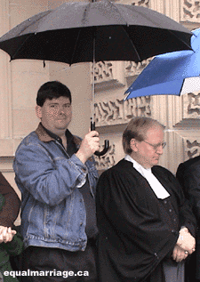 Roles are temporarily switched as Joe Varnell offers protection to lawyer Douglas Elliott during the press conference on the steps of Osgoode Hall (Photo by equalmarriage.ca, 2003)